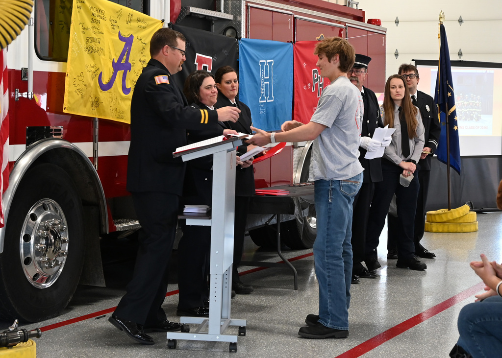 a line of Fire fighters in dress uniform shaking hands with a boy