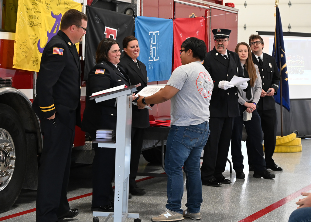 a line of Fire fighters in dress uniform shaking hands with a boy