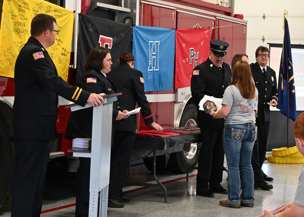 a line of Fire fighters in dress uniform shaking hands with a girl