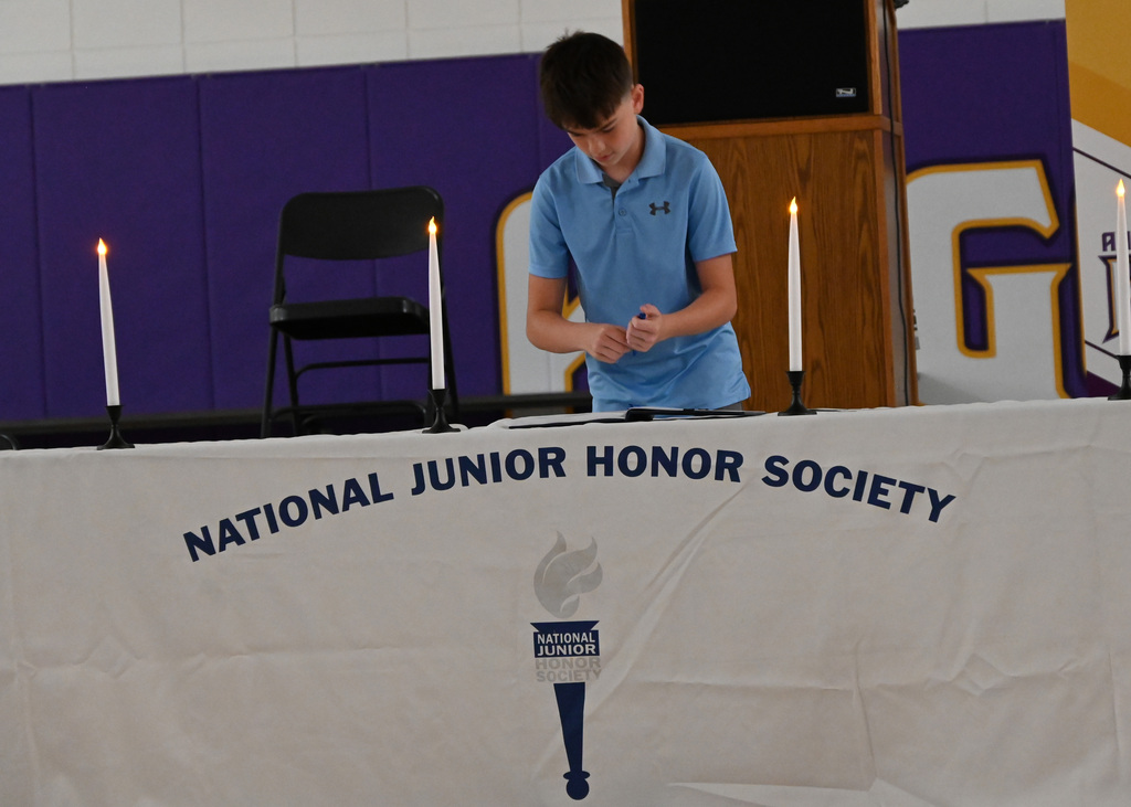boy  at a table with National Junior Honor Society signing a book