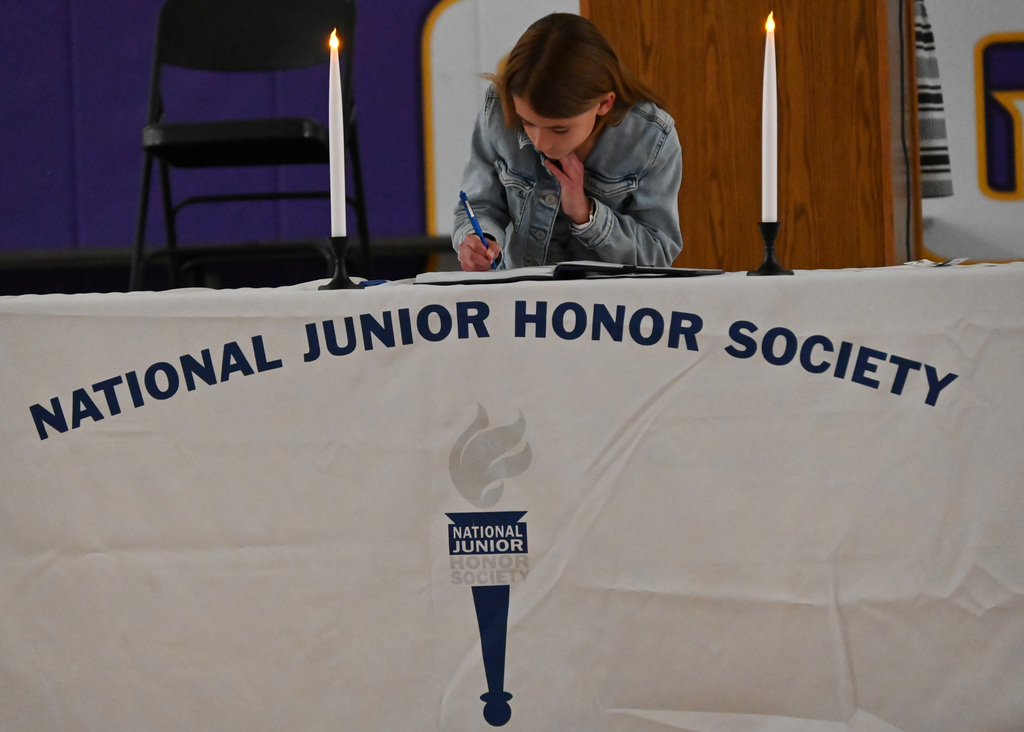 Girl at a table with National Junior Honor Society signing a book