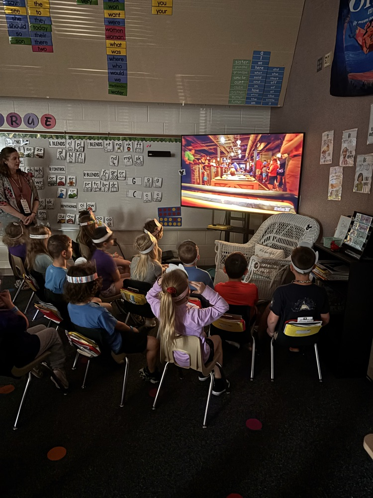children in chairs watching a tv