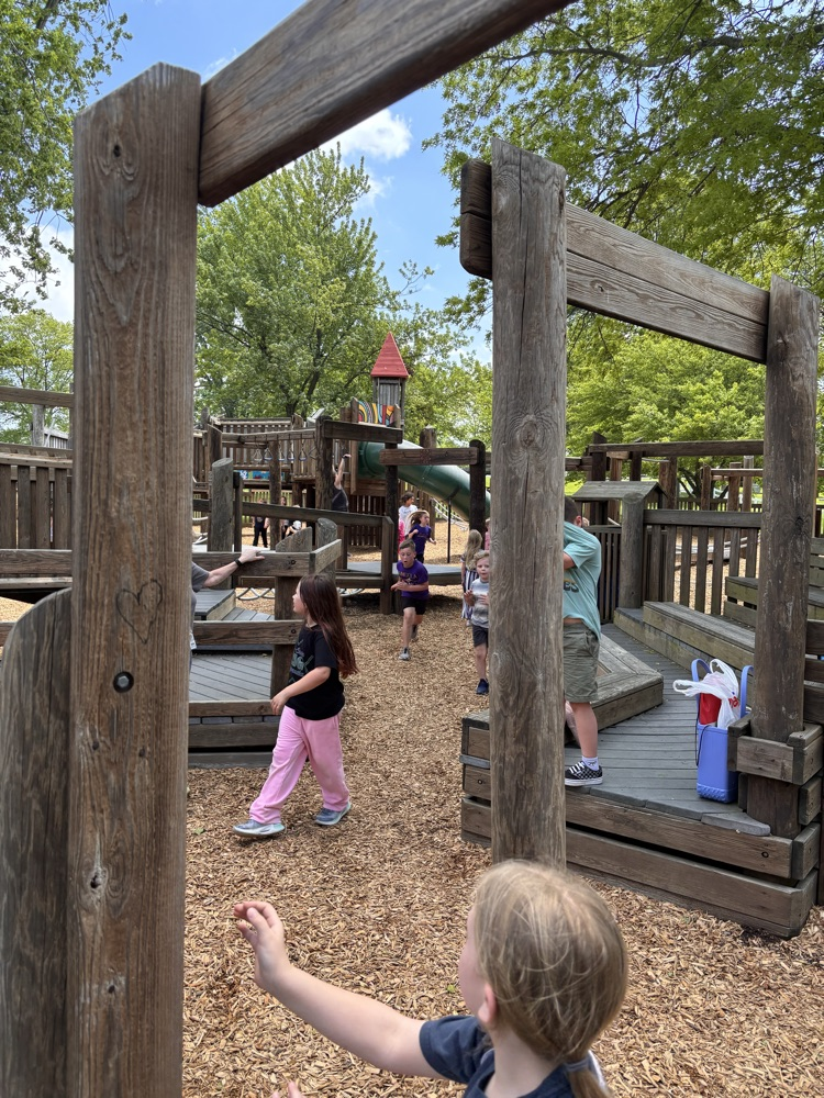 children playin on a large wooden play area