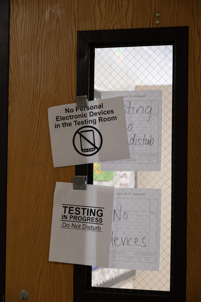 A door with signs on it that say No personal electronic devices testing in progress