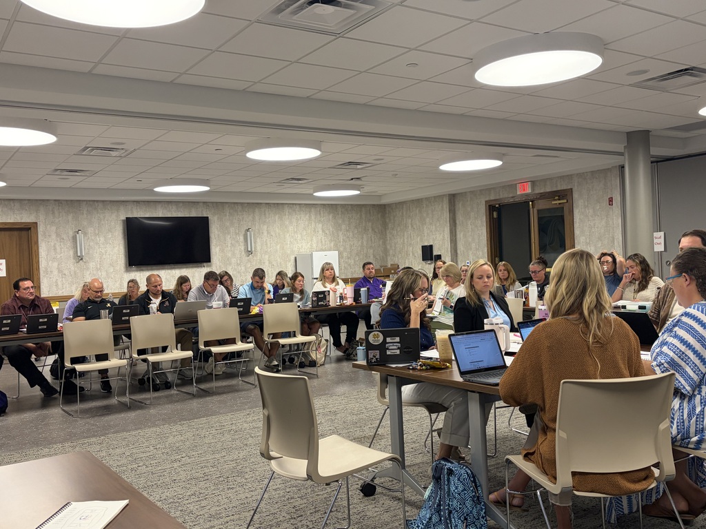 large groupl of people sitting around tables working on laptops