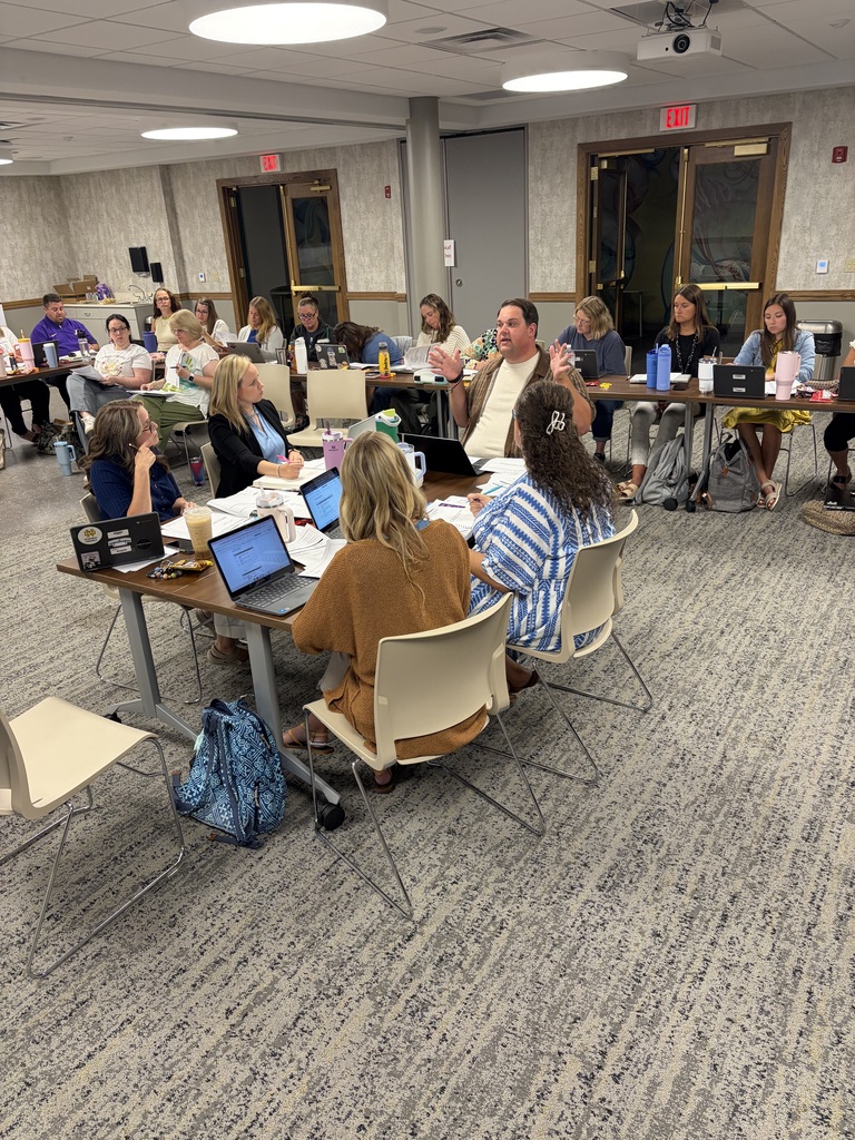 large groupl of people sitting around tables working on laptops