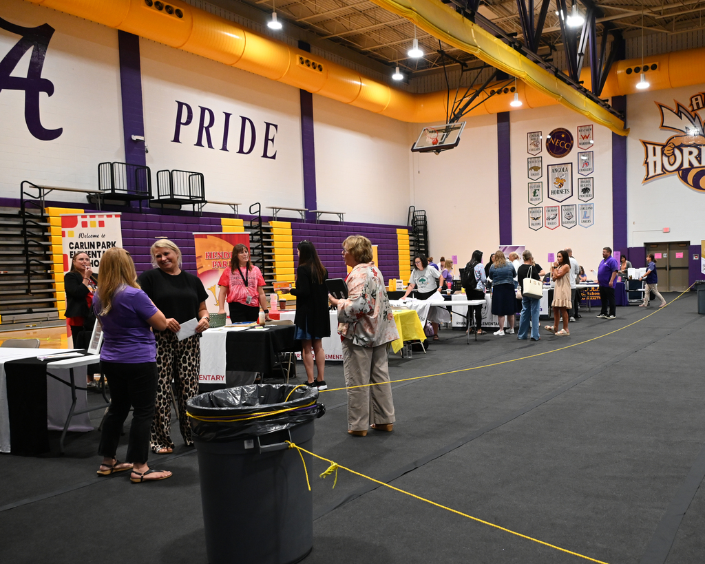 people standing talking around tables in a gyn