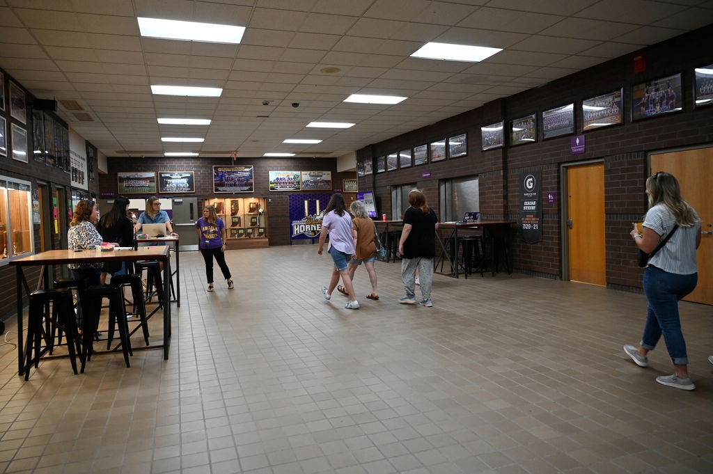 entry way of a school with people walking around in it and sitting at tables