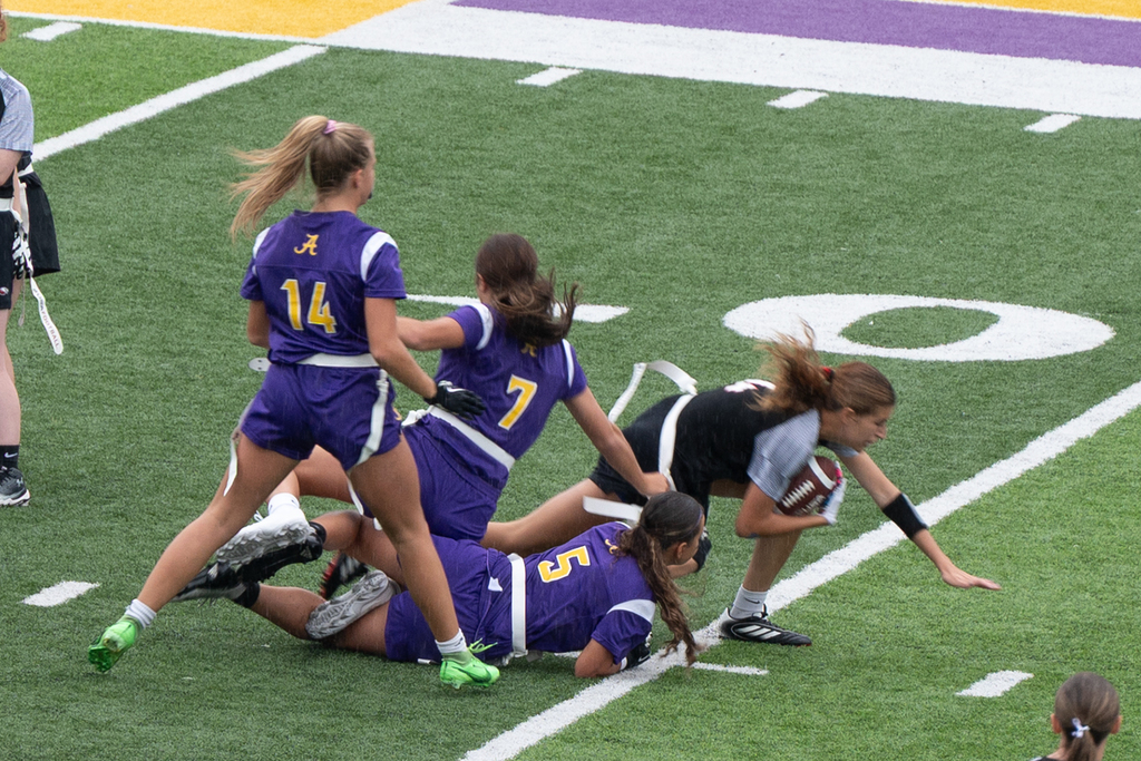 girls in hornet jersey tackling a player in a black uniform