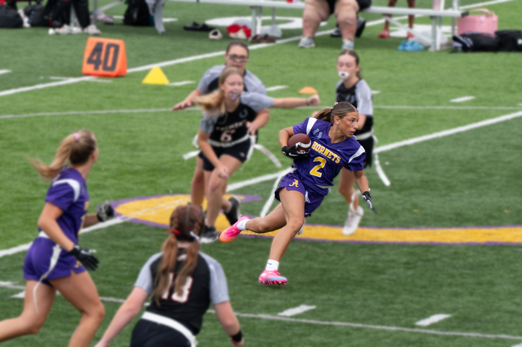 girl in hornets jerasy running wiht a football
