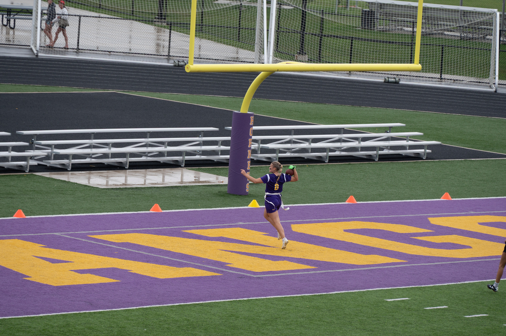 Girl jumping in front of goalposts with football