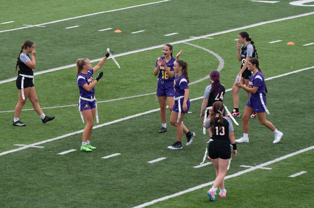 Girls flag football team cheering holding up flag