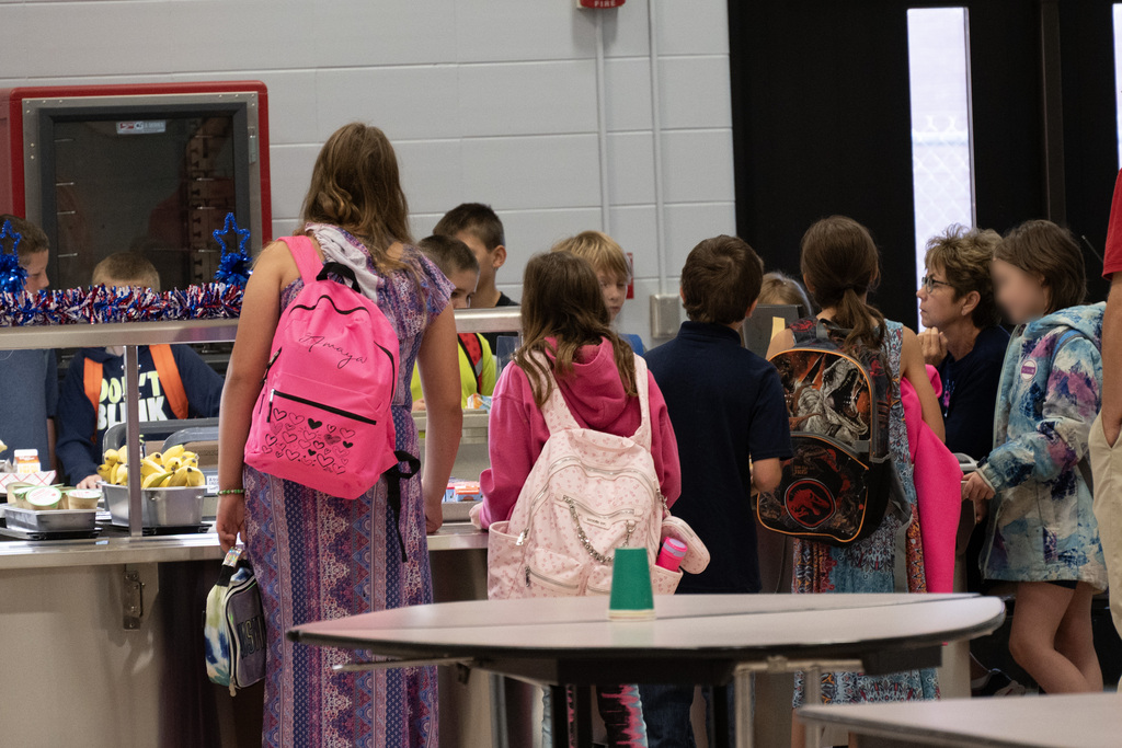Large group of children getting in line at cafeteria stand