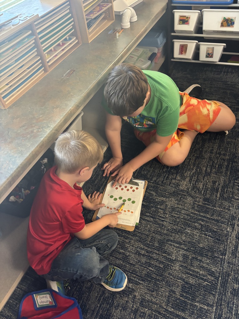 two childern sitting on floor working on a paper