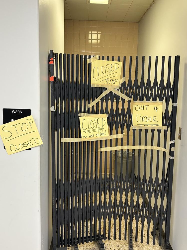 Restroom gated off with multiple signs saying "closed", "stop" and "out of order".