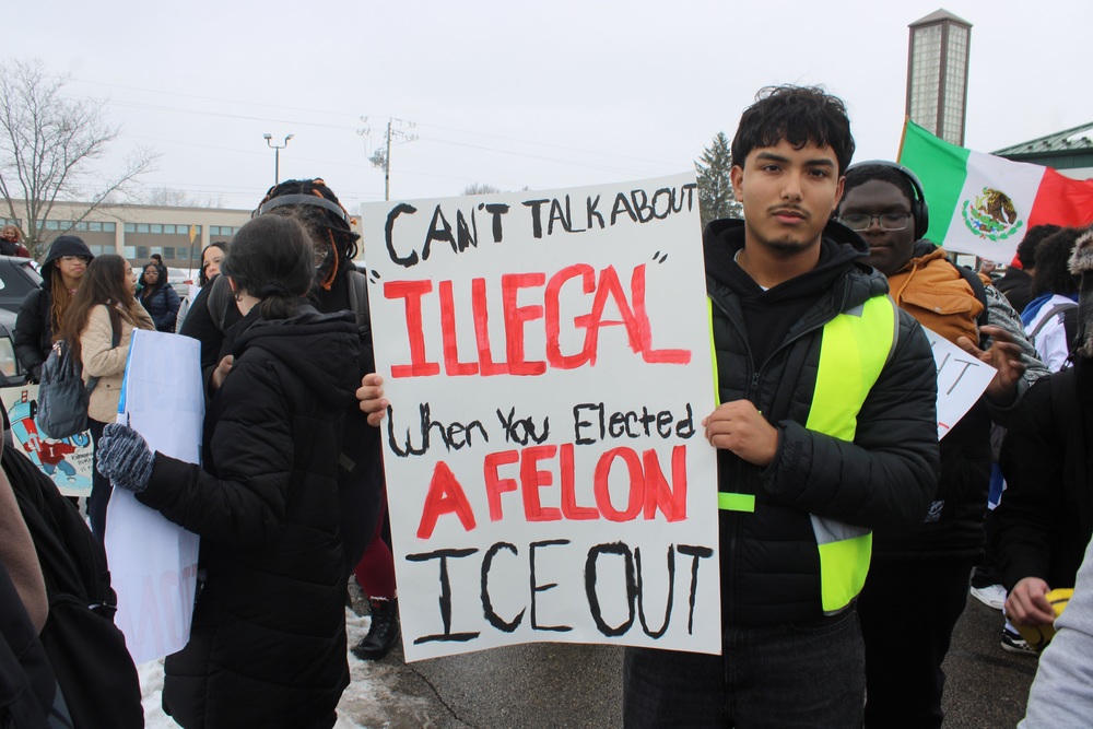 Student holds up posters at Anti ICE protests