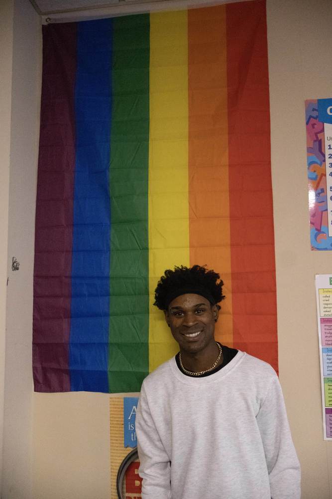 Clifton Jett stands in front of Pride flag.