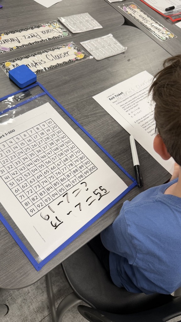 2nd grade students using a 100s chart to answer questions on their exit ticket.