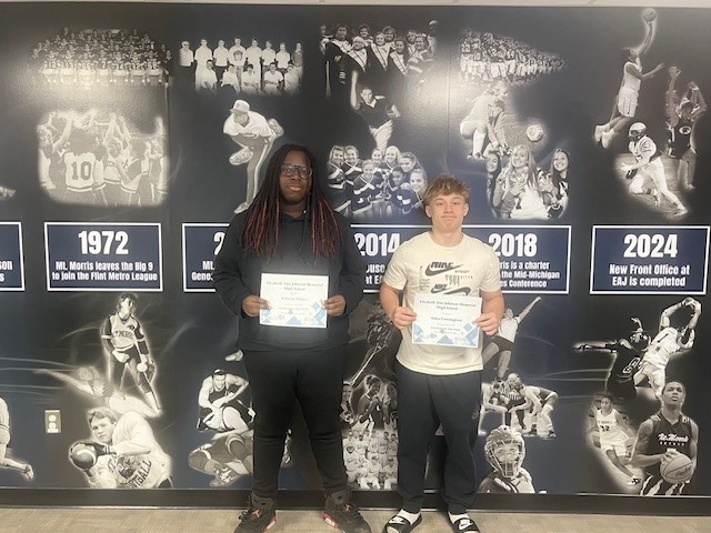 Students of the Week -X'Zaviar (left) and Aiden (right) holding thier student of the week certificates in front of the Navy and White athletic  mural.