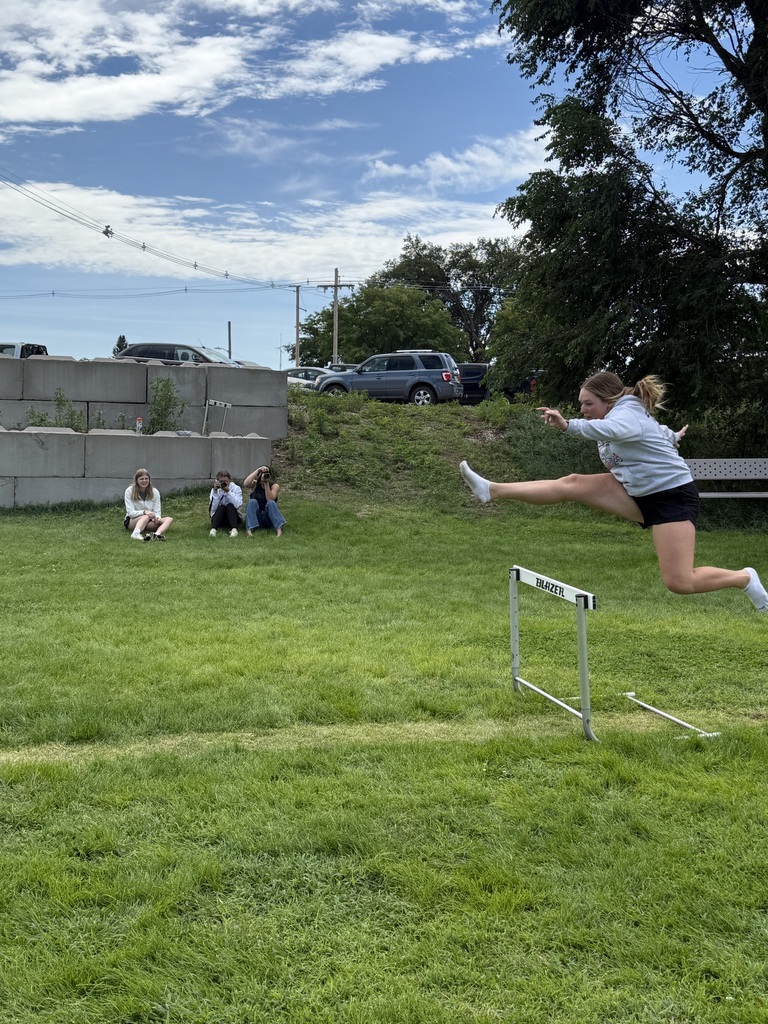 Student hurdling while three take her picture