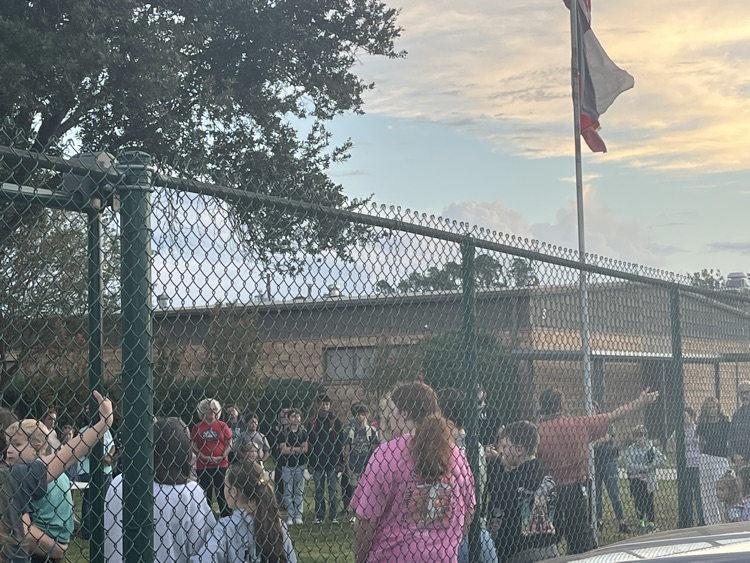 Students and parents gathered around the flag pole.