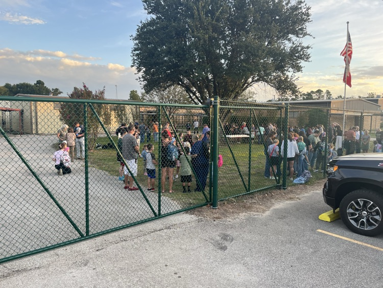 Students and adults gathered around the flag pole