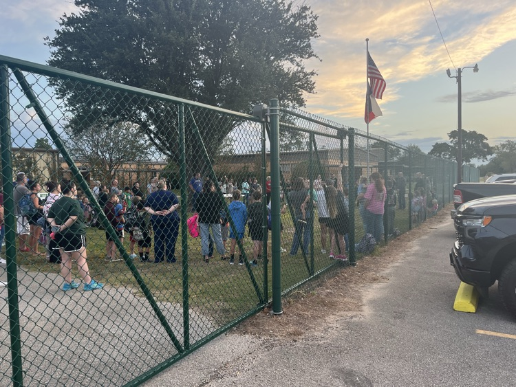 Students and adults gathered around the flag pole.