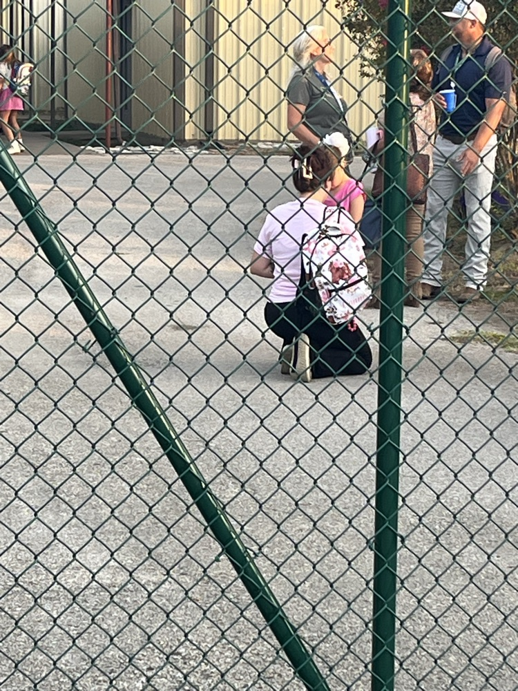 Students and adults gathered around the flag pole.