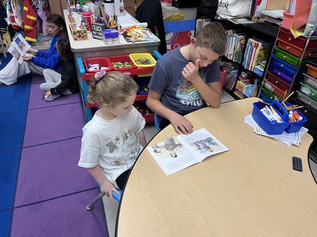 Older students are reading books to younger students