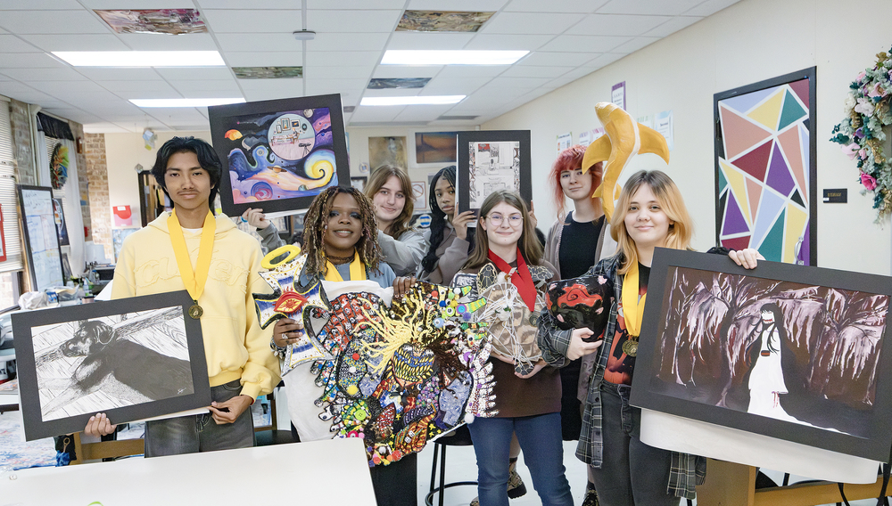 Students displaying artwork in classroom