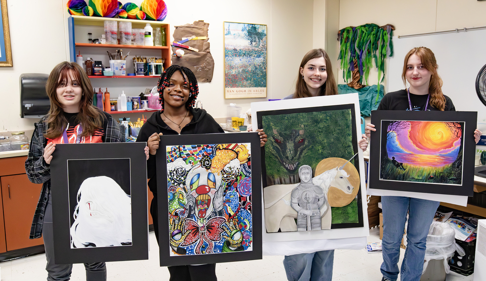 Four students holding their artworks