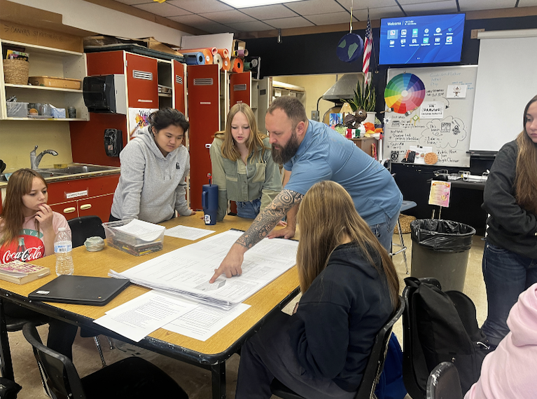 Aaron Fuller shows high school students a blue print during a visit to Art students