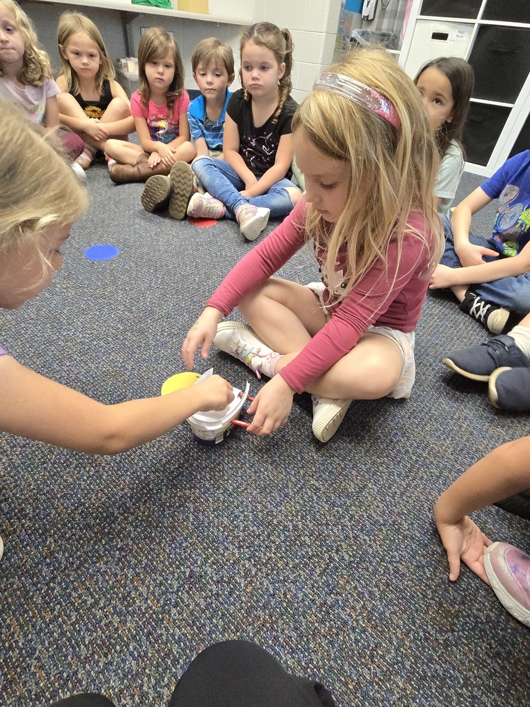 a girl using a STEM tool and another student helping while others watch