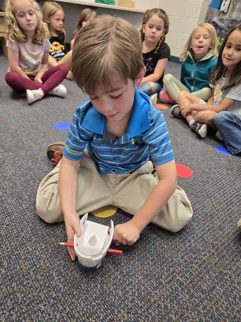 a boy using a STEM tool and other students watching
