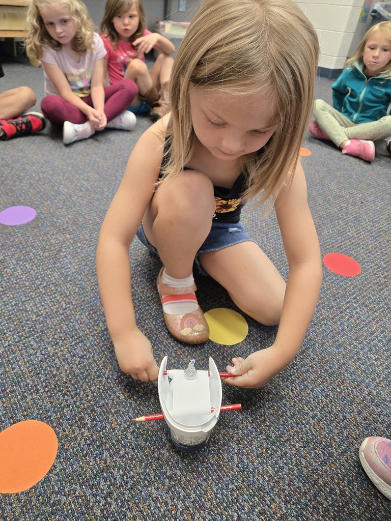 a girl using a STEM tool and other students watching