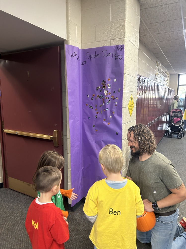 students standing a spider jump game with an adult