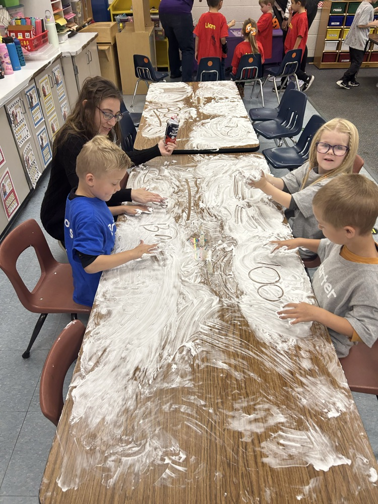 adult helping students write in shaving cream