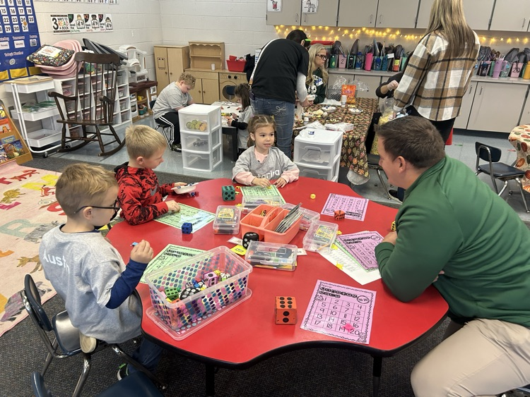 adult helping student with activity at red table