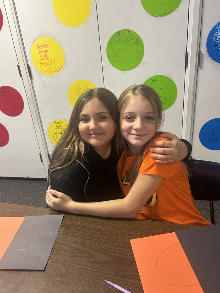two girls hugging at table