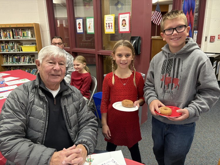 two kids with grandpa at Veterans day celebration 