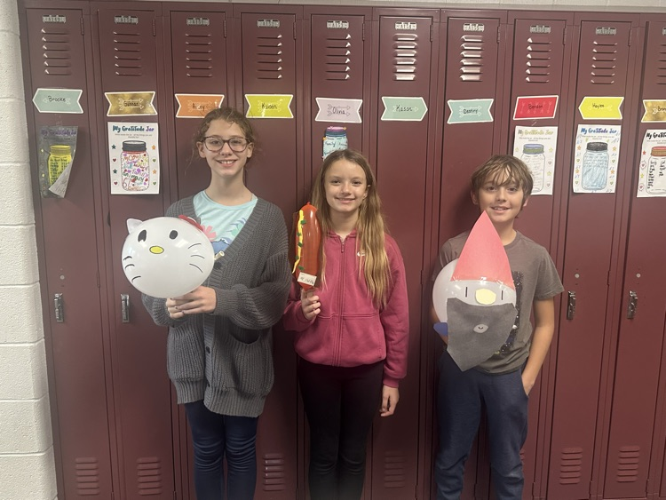 3 kids standing in front of lockers holding balloons