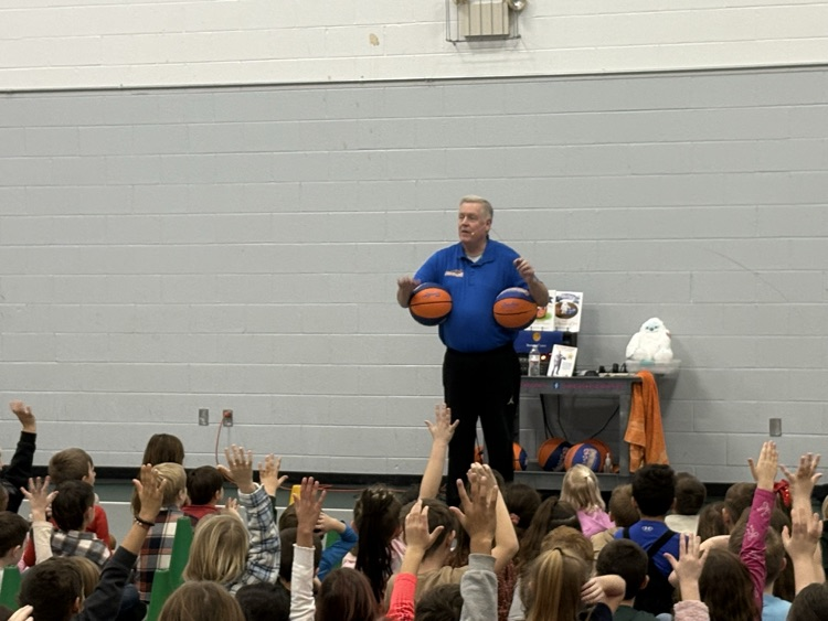 man holding basketball standing in front of studentd