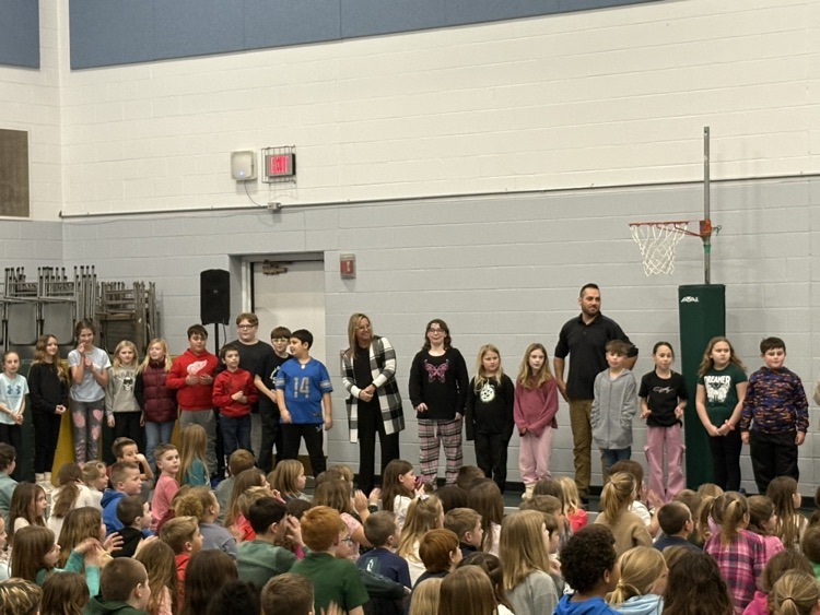 kids and two adults standing in front of student body