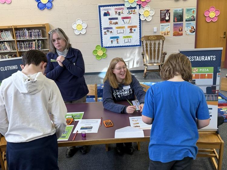 students at a table getting help from adults at reality fair