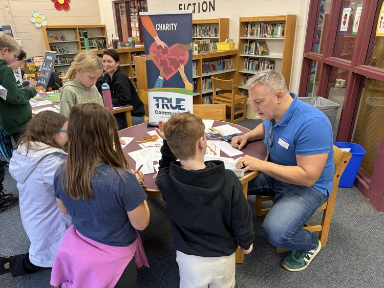 students at table with adult participating in Reality Fair