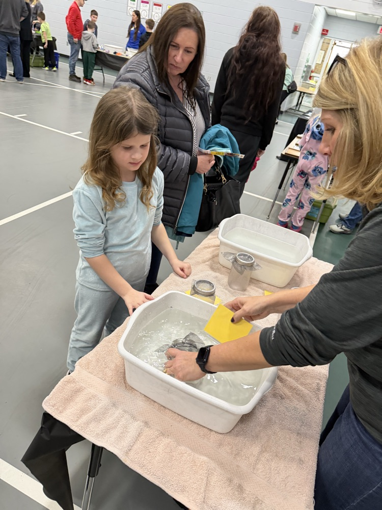 student with adult playing in tub of water