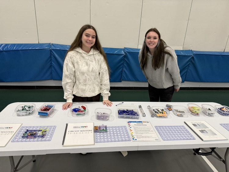 two students standing by table