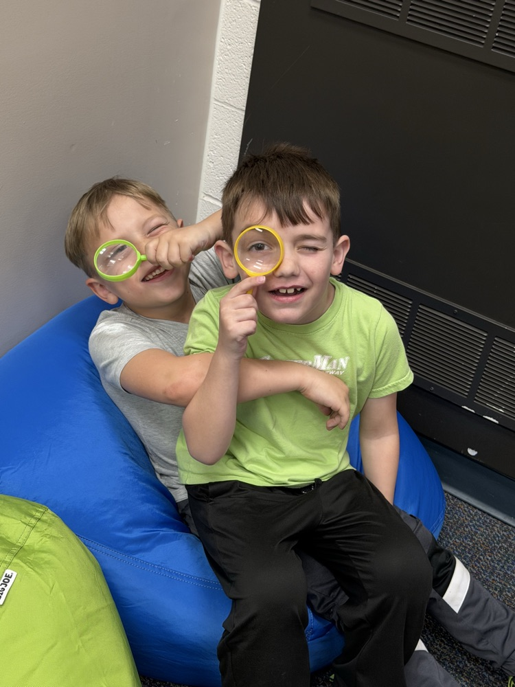 two boys on bean bags with magnifying glasses