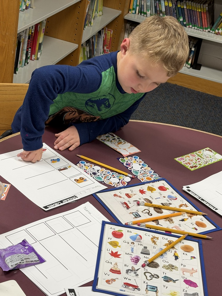 student using stickers and alphabet chart