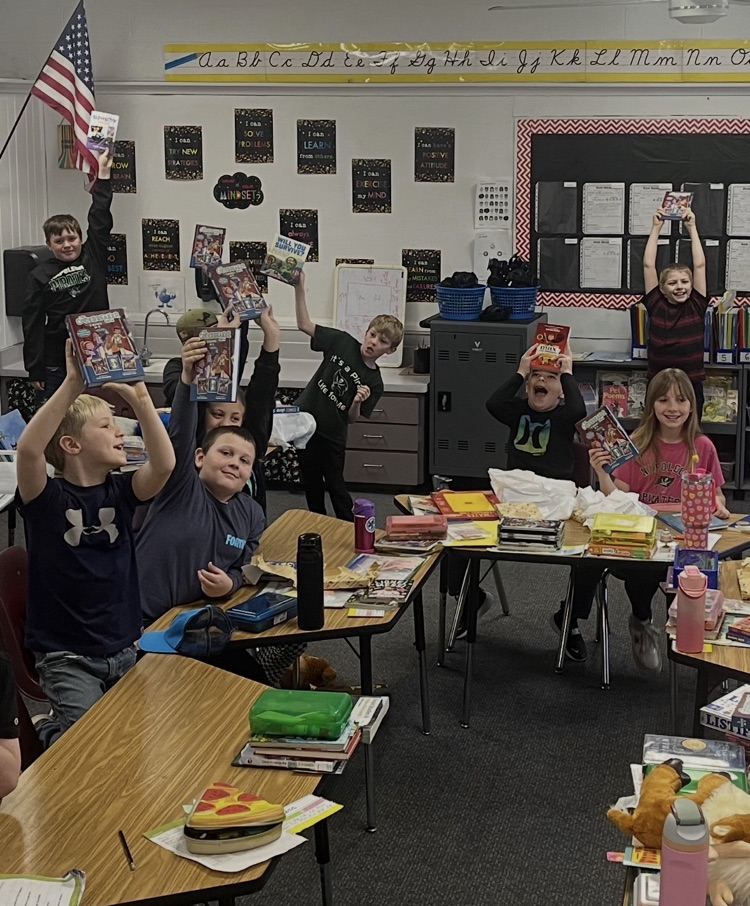 students in classroom holding up books
